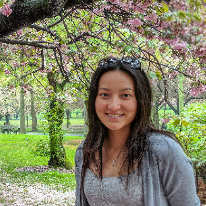 Felicia Chao surround by cherry trees that are blooming.