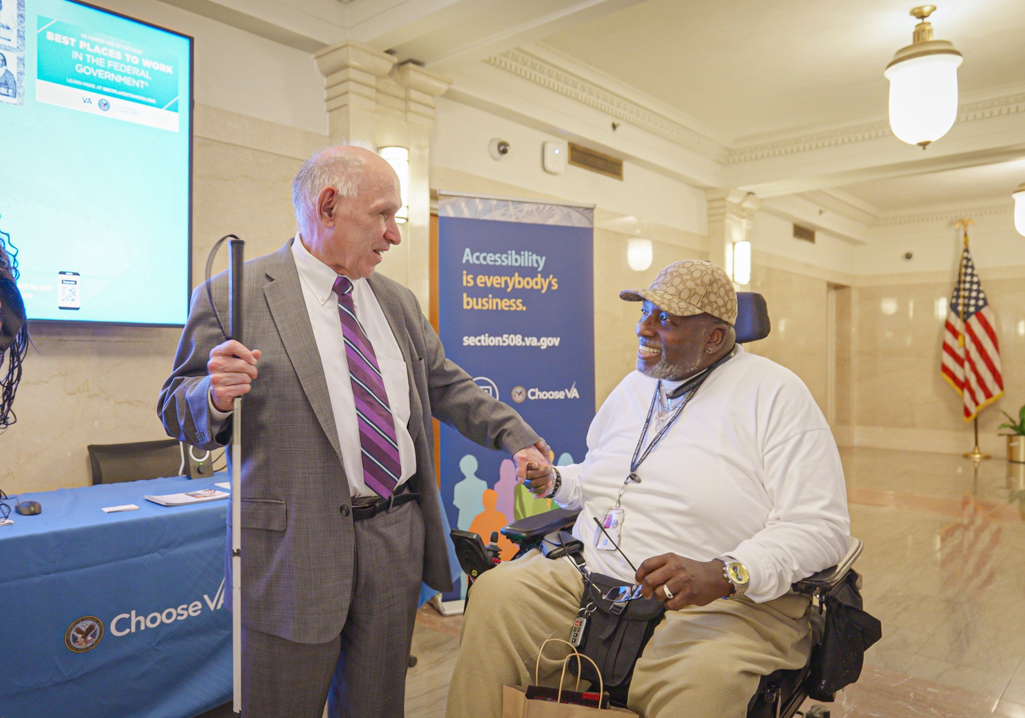 Blind gentleman having a conversation with a Veteran in a wheelchair.