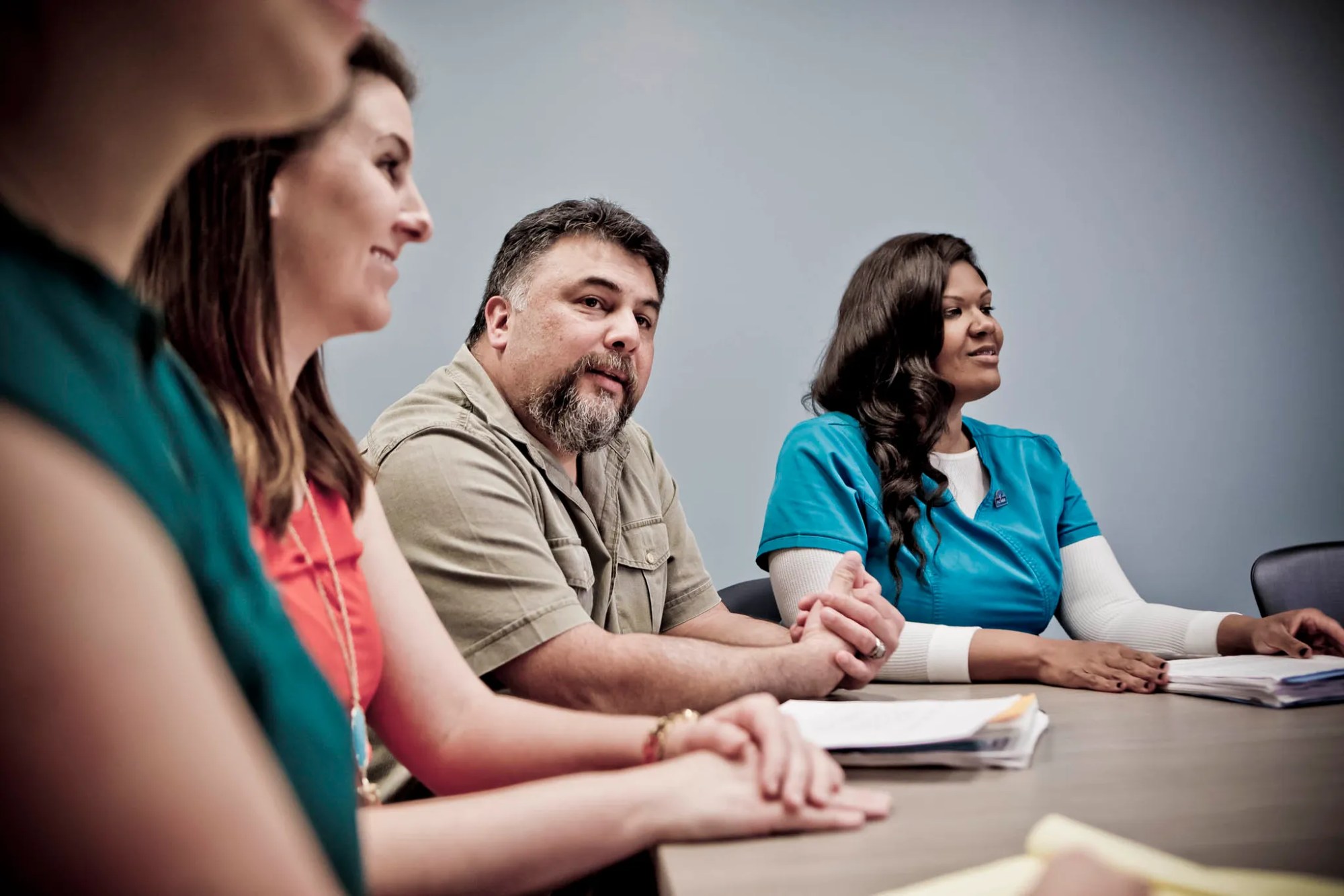 Multiple people sitting around a table listening to a meeting