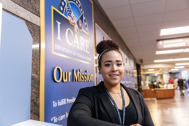 Female standing in front of a I CARE sign at the Department of Veteran Affairs building