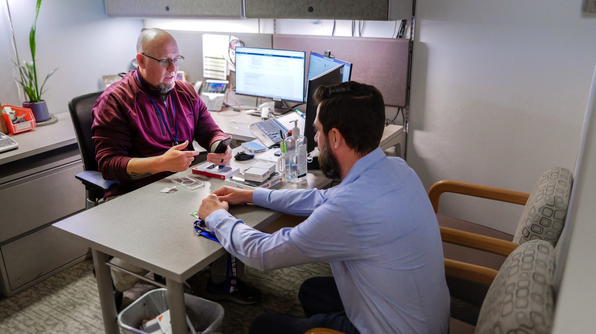 Two IT professionals sitting at a office table setting up iPhones