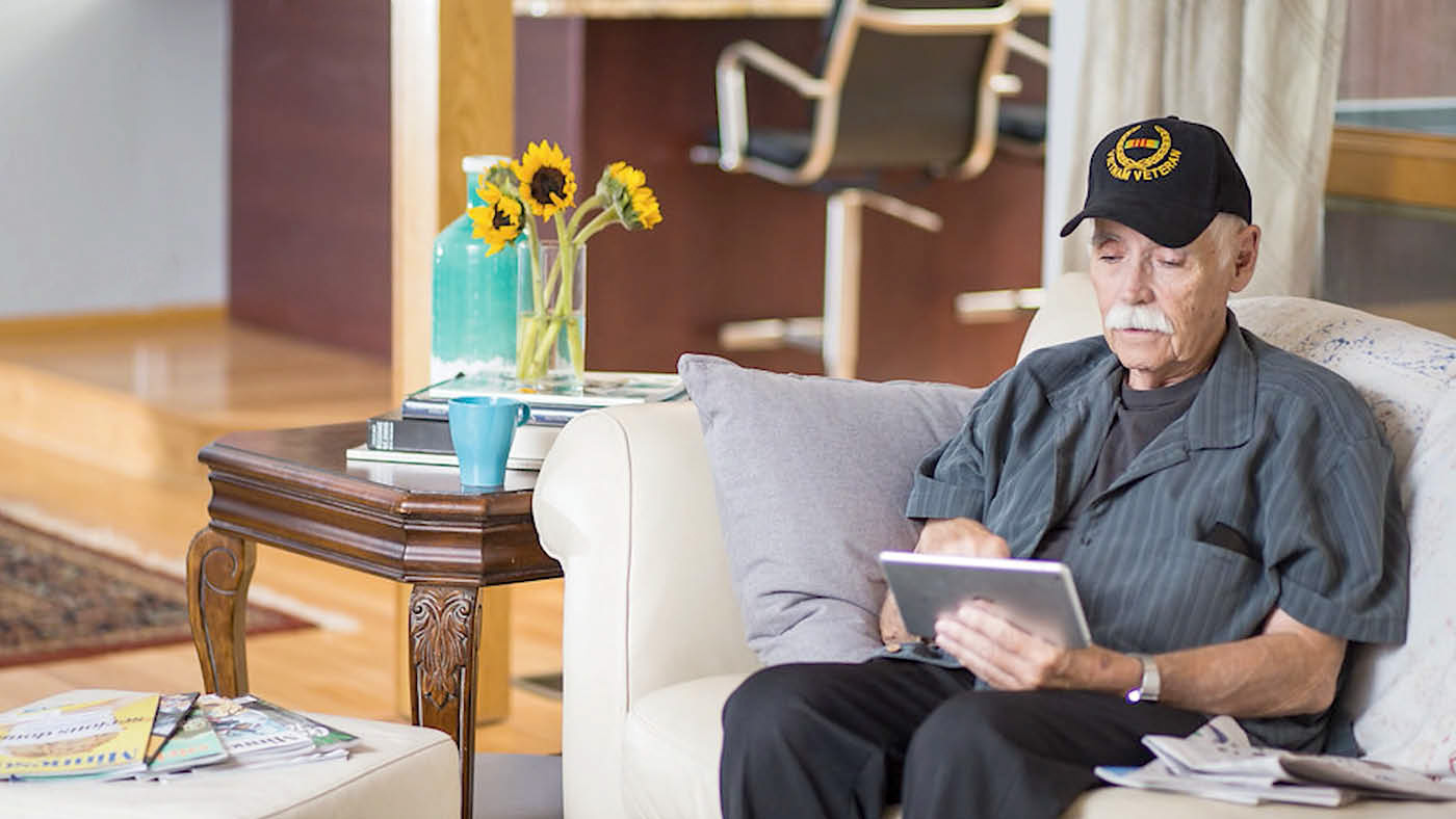 Veteran sitting on a couch and using his mobile device to access VA benefits.