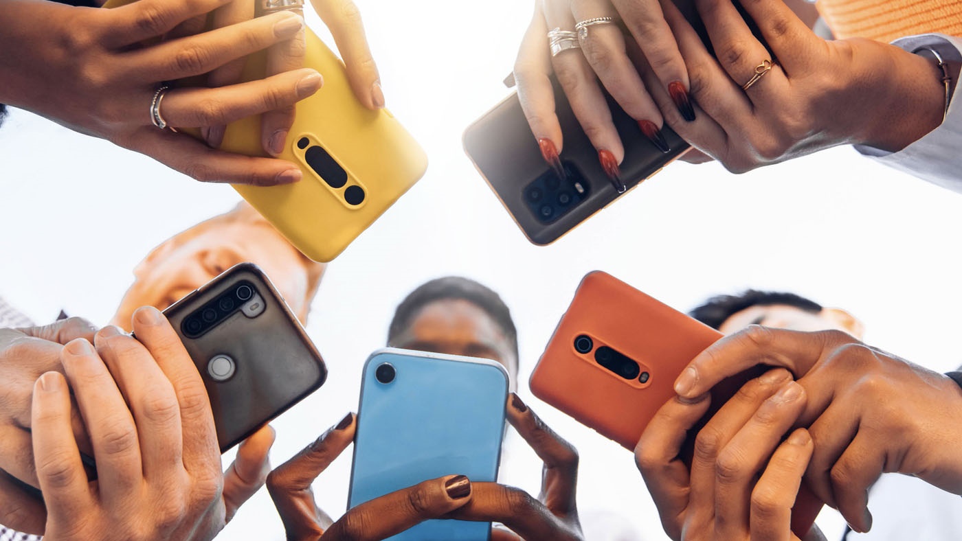 A diverse group of people in a circle holding smart phones.